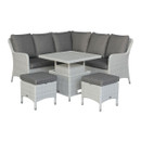 Grey wicker outdoor corner sofa set with dark grey cushions, displayed with the square table raised to dining height and two cushioned stools against a white background.