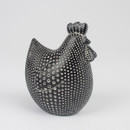 A black and white hen figurine with polka dots stands against a plain white background. The dotted pattern gives it a whimsical appearance.