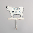 Rusted metal cow-shaped wall hook on a gray background, with "Fresh Milk" in raised letters, conveying a vintage, rustic farmhouse charm.