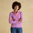 Woman wearing a pink and blue striped long-sleeve polo top with a classic collar, styled with blue jeans against a neutral backdrop.