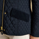 Close-up of a black quilted jacket pocket with corduroy trim and subtle Joules branding stitched into the fabric.