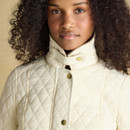 Close-up of the high collar on a cream quilted jacket with gold poppers and diamond quilting.