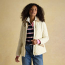 Woman in a cream quilted jacket with tan corduroy accents and gold hardware, layered over a striped rugby top with pink cuffs.