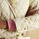 Close-up of a cream quilted sleeve with gold poppers, ribbed pink cuff and diamond-stitched pattern.