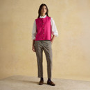 Full-length outfit featuring a vibrant pink sleeveless knitted vest, white ruffled blouse and slim checked trousers with loafers.