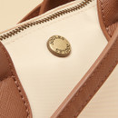 Close-up of the cream bag’s textured tan handle and gold Joules branded button detail on the front.