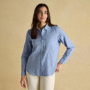 Woman wearing a light blue long-sleeve woven shirt with a subtle check pattern, styled with cream trousers against a neutral backdrop.