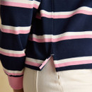 Close-up of the side hem on the striped rugby shirt, showing the small side split and clean stitching above cream trousers.