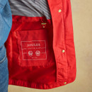 Interior view of a bright red raincoat showing the Joules branded label and lining.