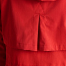 Close-up of the rear storm flap and stitching on a bright red women’s raincoat.
