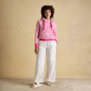 Woman styling the pink striped hoodie with wide-leg white trousers and sandals for a relaxed look.