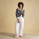 Model wearing a navy and white striped sweatshirt paired with relaxed white linen trousers and pink sandals.