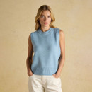 Women’s sky-blue sleeveless knitted vest with a ribbed crew neckline, styled with cream jeans against a neutral studio backdrop.