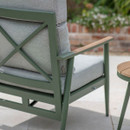 Rear angle close-up of the sage green reclining armchair, showing the cross-back frame and wooden-look armrest with eco mist cushions.