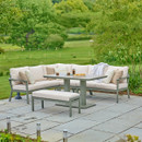 A view of a LG Outdoor Rectangular Modular Corner Garden Furniture set with an adjustable table lifted up on a patio next to a green field