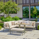 A view of a LG Outdoor Rectangular Modular Corner Garden Furniture set with an adjustable table lifted up on a patio next to a house