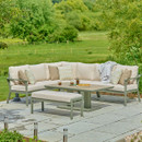 A view of a LG Outdoor Rectangular Modular Corner Garden Furniture set with an adjustable table lowered down on a patio next to a green field