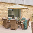 An LG outdoor dining set with a large umbrella, featuring wicker chairs and a round table with a Lazy Susan on a stone patio against a modern building backdrop.