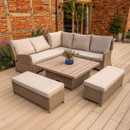 Rattan corner garden seating set with beige cushions surrounding a square slatted-top table, displayed on a timber deck beside planted borders.