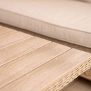 Close-up of a slatted wood-effect tabletop beside a beige outdoor seat cushion.