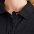 Close-up detail of the black polo shirt collar and button placket, highlighting contrasting buttons and textured fabric.