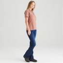Side view of a woman wearing the dusty pink fitted polo shirt styled with blue jeans and dark ankle boots, photographed against a neutral grey studio background.