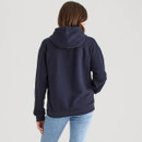 Back view of a navy blue pullover hoodie showing a roomy hood, raglan-style sleeves, and ribbed hem. The model wears light blue jeans, photographed against a light grey background.