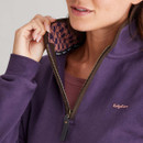Close-up of the quarter-zip collar on the purple sweatshirt, showing the brown trim, metal zip, and patterned inner lining in pink and purple houndstooth.