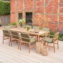 Kettler Meadow 8 seat garden dining set with rectangular wooden table and eight green cushioned rope-back chairs on a patio against a red brick wall.