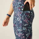 Close-up of dark floral print leggings showing the side phone pocket with a smartphone inside.