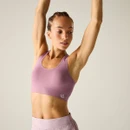 Model wearing mauve seamless sports bra and lilac shorts, arms raised overhead.