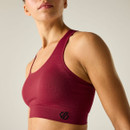 Close-up side view of a burgundy sports bra, showing the seamless fabric and logo on the lower band.