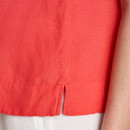 Detail view of the side hem on a red linen top, featuring a small side vent for ease of movement.