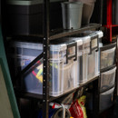 Set of clear storage boxes with black clip handles neatly arranged on metal shelving in a garage, filled with tools and equipment.