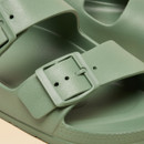Close-up of a sage green sandal highlighting the textured, adjustable buckle and smooth upper strap.