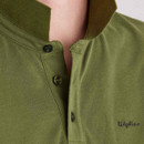Close-up of a green polo shirt collar and button placket, highlighting the textured fabric and tonal buttons.