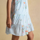 Close-up of the tiered skirt on a light blue striped dress featuring scattered floral prints and fine vertical stripes.