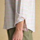 Close-up of a man’s white multicoloured check Oxford shirt showing rolled sleeve with contrast inner cuff detail.