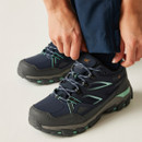 Person fastening navy waterproof walking shoes with cushioned soles and lace fastening.