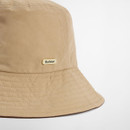 Close-up of the beige bucket hat side showing the stitched brim and Barbour metal logo badge.