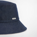 Close-up of the Barbour metal badge on the side of the navy denim bucket hat.