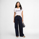Full-length view of the white Barbour logo T-shirt worn with wide-leg dark denim jeans and a small tote bag.