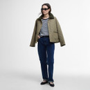 Model in a navy and white striped Barbour T-shirt, dark blue jeans and a quilted khaki jacket with sunglasses.
