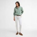 Full-length view of the sage green Barbour half-zip sweatshirt worn with white jeans, brown belt and brown loafers.