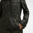 Close-up of front lower flap pocket with Barbour embroidery and press-stud fastening on dark olive waxed fabric.