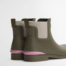 Angled rear view of olive green Barbour Chelsea boots showing twin pull tabs, elastic gussets and pink Barbour branding at the heel.