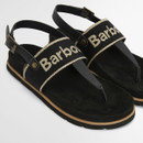 Close-up of black Barbour sandals showing woven logo strap, leather toe post and suede-effect footbed.