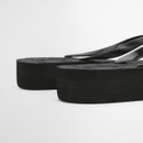 Close-up of black flip flops showing layered foam sole and smooth rubber straps
