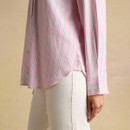 Side detail of a pink striped long-sleeve shirt showing the curved hem, cuff, and embroidered logo near the side seam.