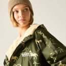 Close-up of the model in a beige beanie with the changing robe draped over the shoulder, showing the cream fleece lining and horse print.